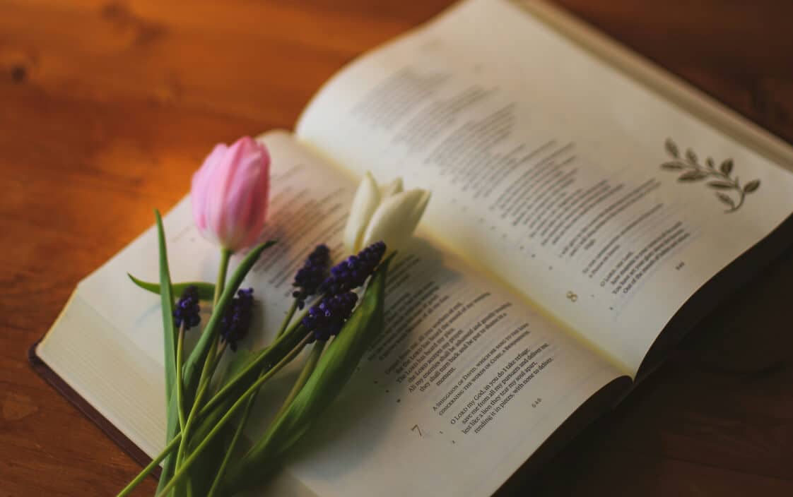 An opened book showing Funeral Verses for Dad with pink and white tulips